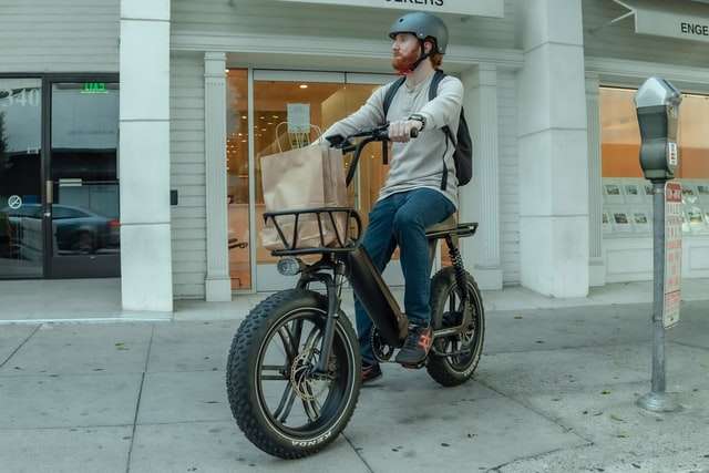 Man on electric cargo bike parked on sidewalk