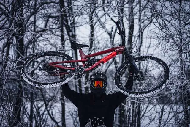 Mountain biker lifting mountain bike in the snow