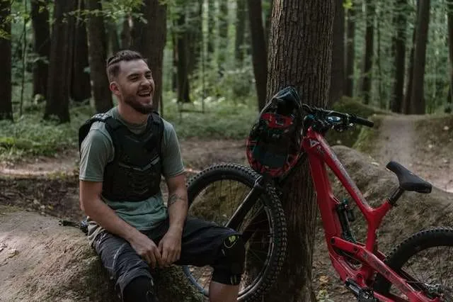 Man laughing beside all mountain bike on trail