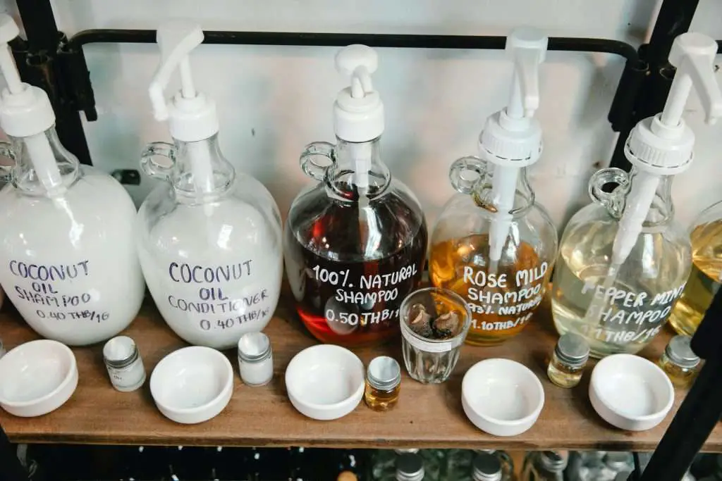Different natural shampoos on wooden shelf