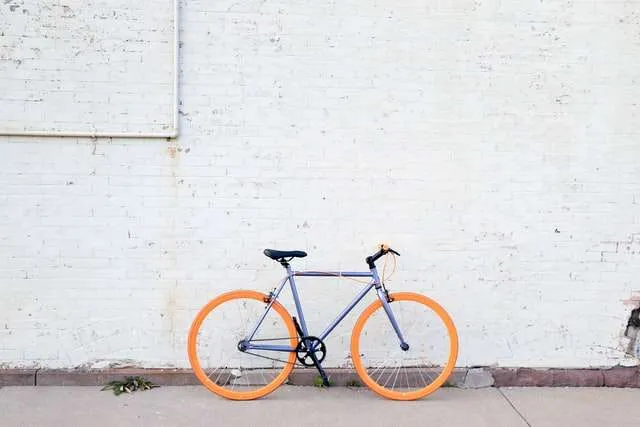 beautiful purple framed bike with orange tires against white wall