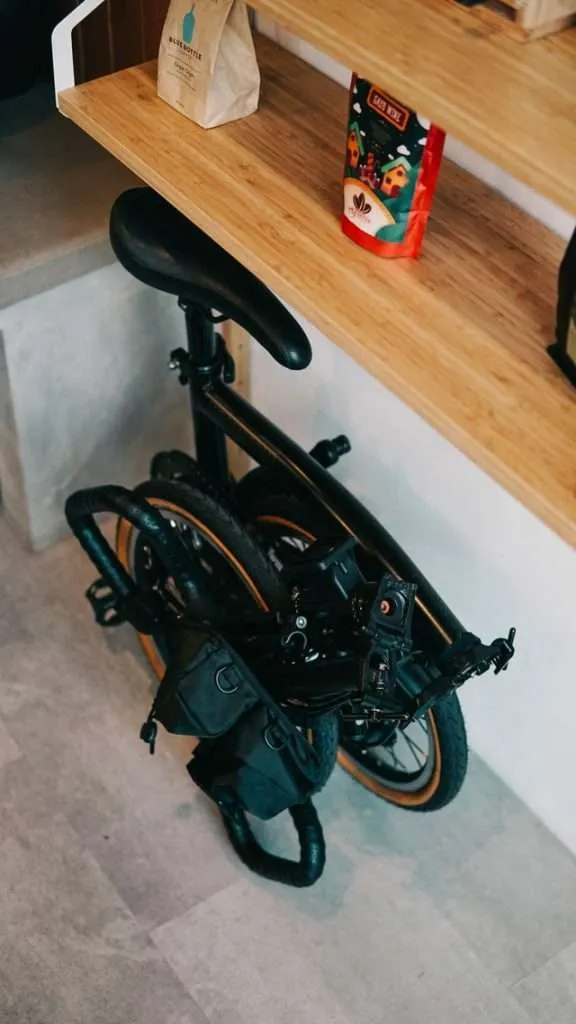 Black folding bike stored under wooden desk
