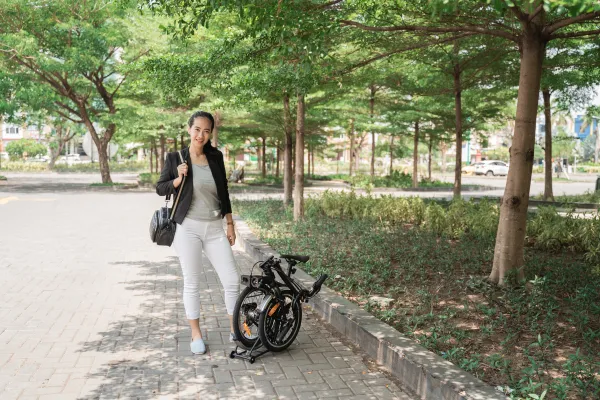 Lady commuter standing beside black foldable bike