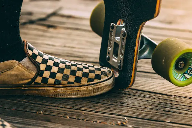 Checkered vans shoes beside skateboard