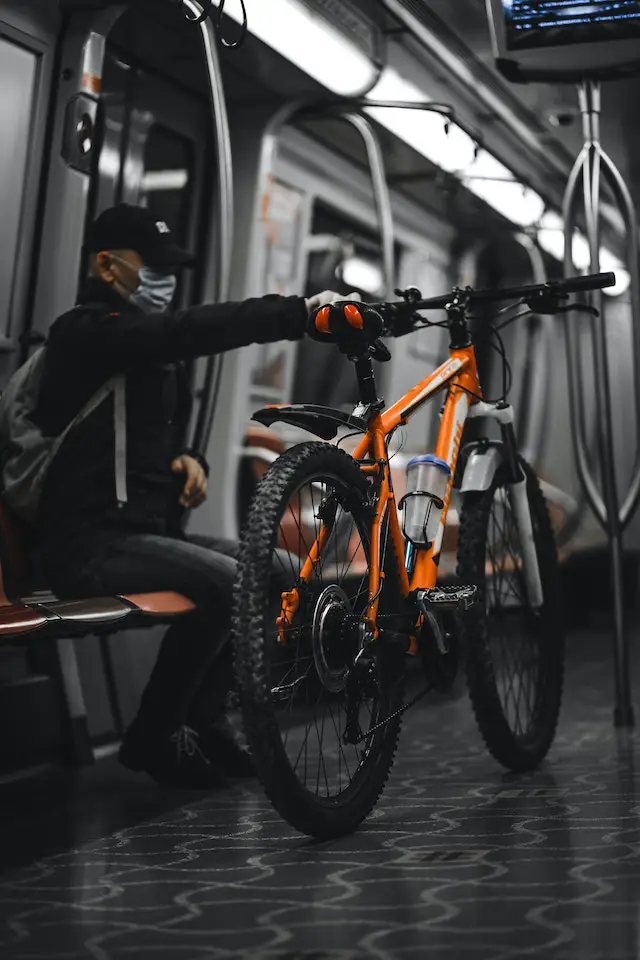 man holding his orange mtb inside a train